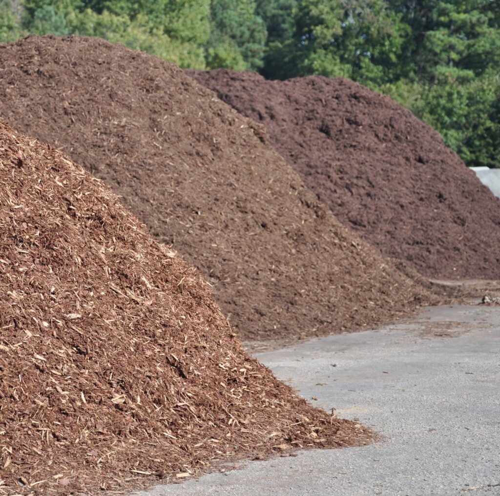 Piles of bark mulch in varying shades, showcasing different types for landscaping applications, emphasizing moisture retention and soil protection benefits.