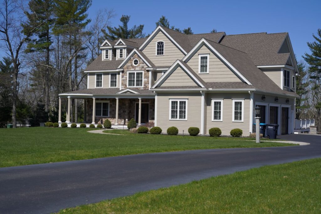 Modern home with stone accents, manicured lawn, and clear blue sky, showcasing enhanced curb appeal and landscaping features.