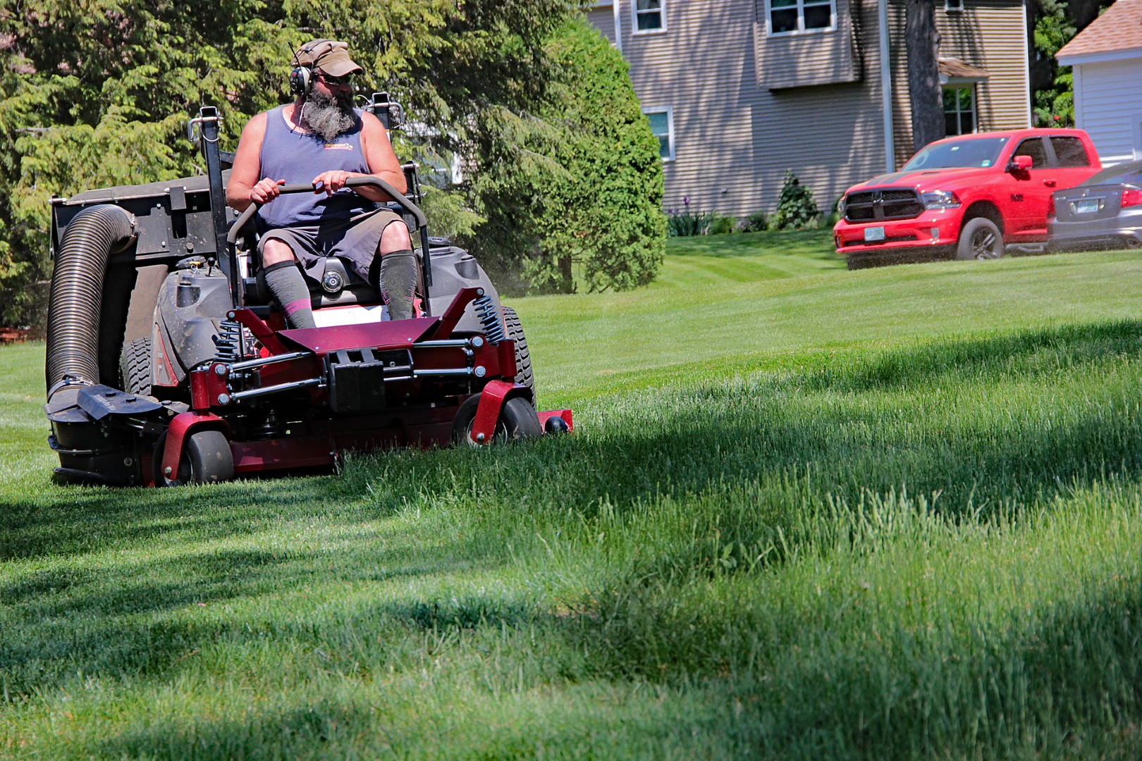 Man operating a riding lawn mower for professional grass maintenance, promoting healthy turf and curb appeal in a residential landscape.