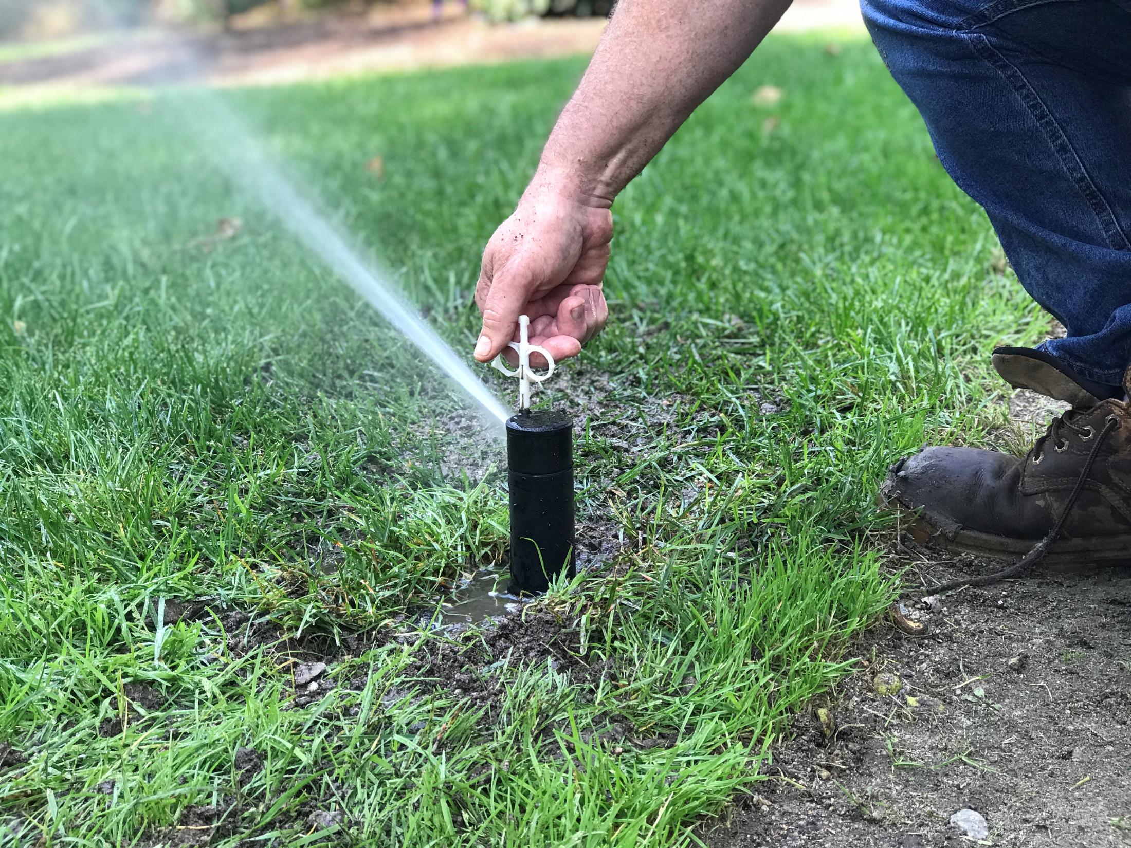 view of a hand adjusting a lawn sprinkler head