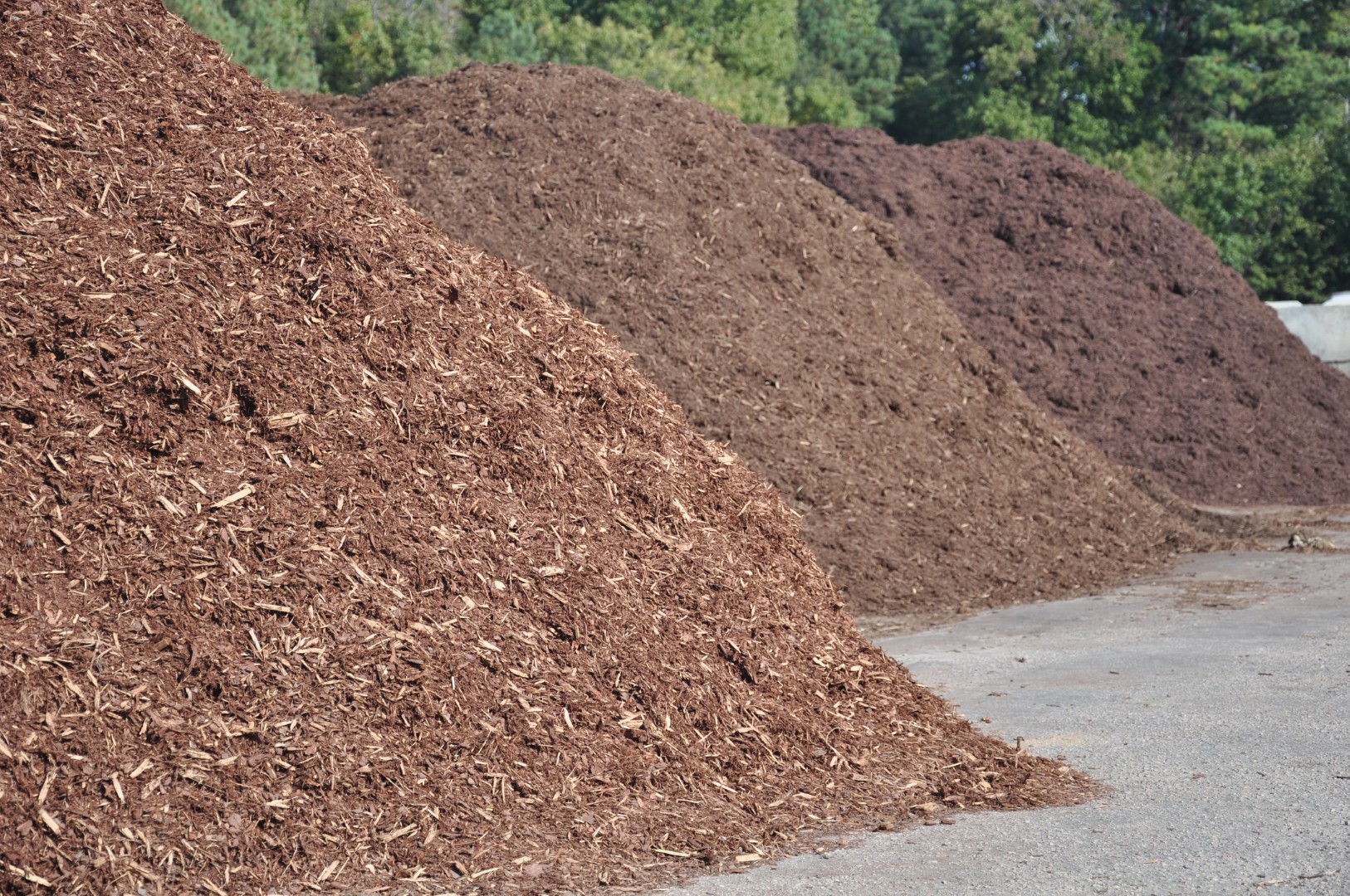 Piles of rich brown mulch at a landscaping materials yard, highlighting locally sourced products for sustainable gardening in Bedford, NH.