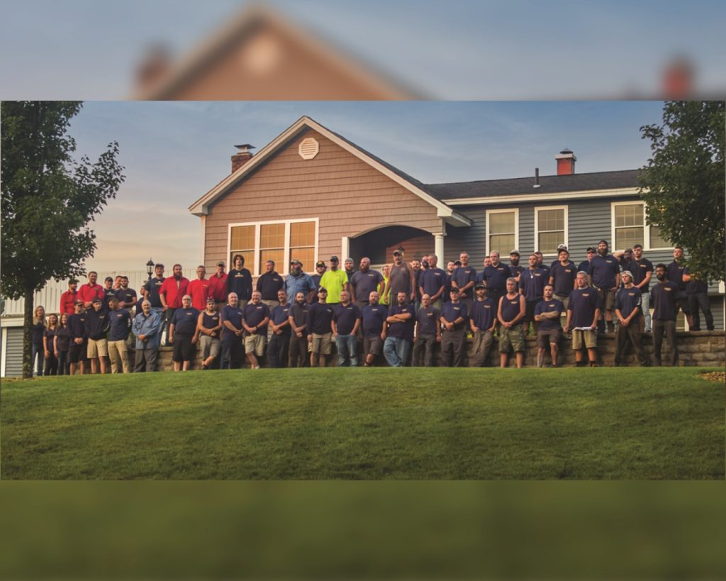 Groundhog Landscaping team posing in front of a house, showcasing professionalism and teamwork in landscaping services.