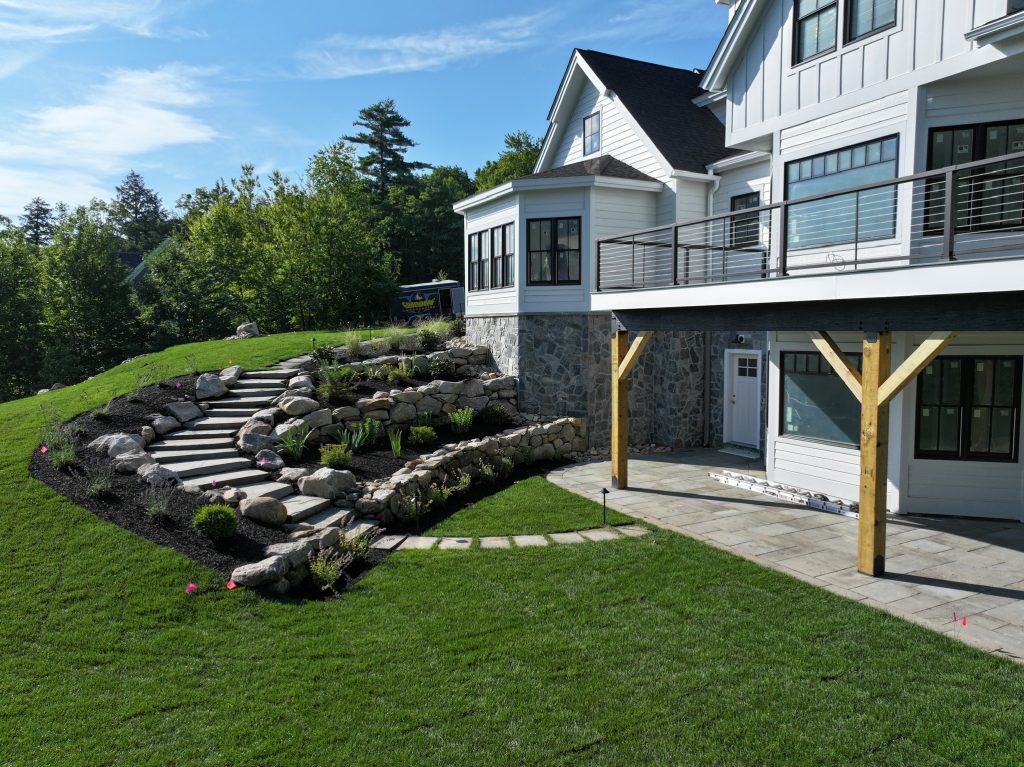 Landscaped yard featuring a stone pathway, lush green grass, and a modern home exterior, illustrating Groundhog Landscaping's quality outdoor transformation services.