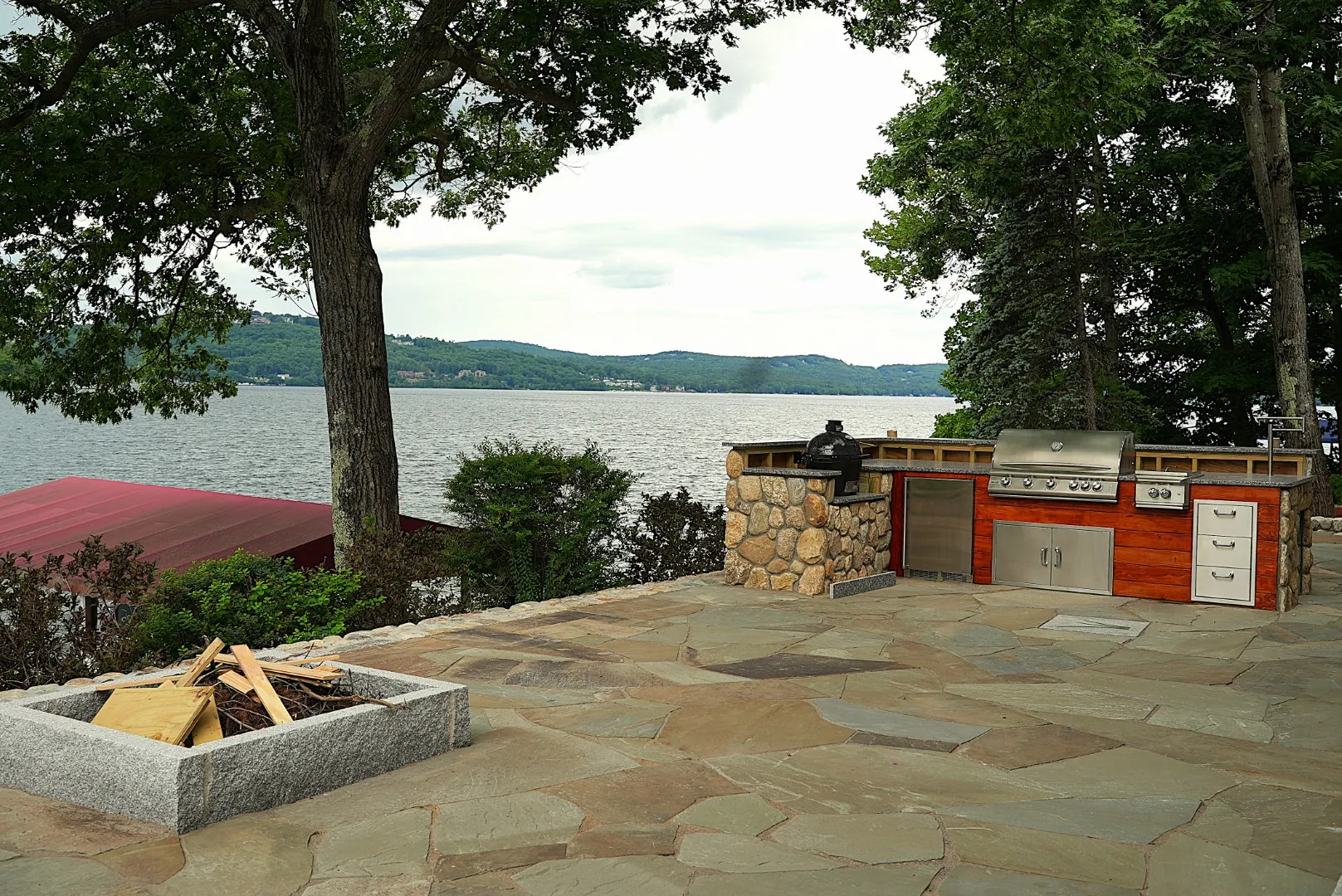 Custom outdoor kitchen and flagstone patio overlooking lake by Groundhog Landscaping