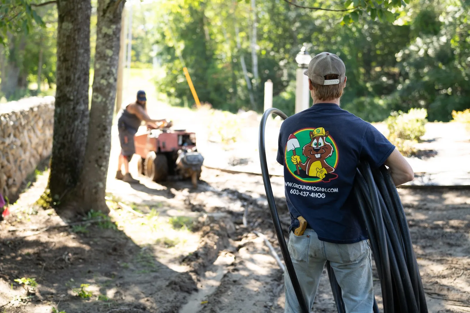 Groundhog technician handling irrigation pipe and fittings for lawn sprinkler installation
