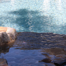 Londonderry Pool Patio featuring a serene water edge with natural stone detailing, showcasing the aesthetic appeal of hardscaping in outdoor living spaces.