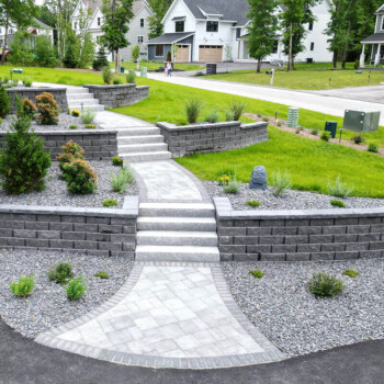 Paver patio and walkway design by Groundhog Landscaping in Derry, NH, featuring tiered retaining walls