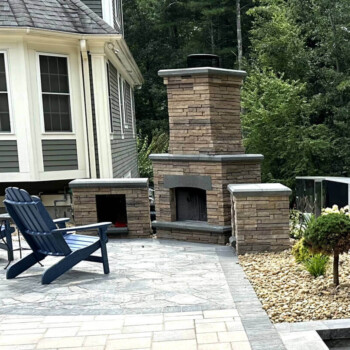 Stone patio and outdoor fireplace design by Groundhog Landscaping in Derry, NH.