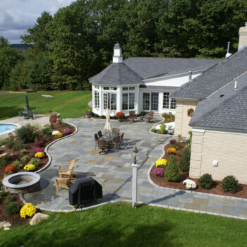 Stone patio and walkway design with landscaping and outdoor seating area in Derry, NH.