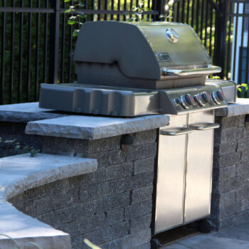 Outdoor kitchen hardscape with grill and stone countertops by Groundhog Landscaping in Derry, NH.